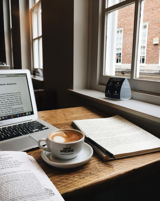 An office desk with a cup of coffee and a laptop on it